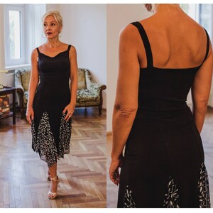 May include: A black sleeveless dress with a white floral print on the bottom half. The dress has a scoop neckline and a fitted bodice.