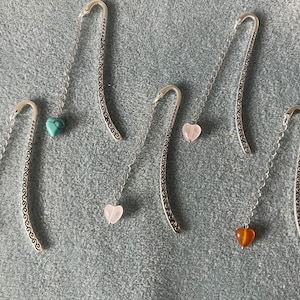 Peut inclure: Six marque-pages en argent avec des pierres en forme de cœur. Les pierres sont turquoise, rose, rose, marron et orange.