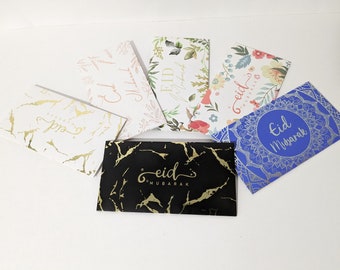 May include: Assortment of six Eid Mubarak greeting cards with different designs. The cards feature floral patterns, marble textures, and a blue card with a silver mandala design. The text "Eid Mubarak" is written on each card.