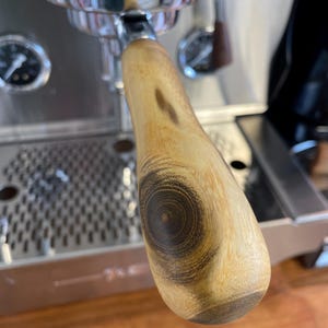 May include: A wooden espresso machine handle with a dark brown wood grain pattern.