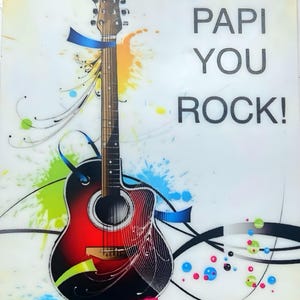May include: Acoustic guitar illustration with a red and black body, adorned with blue ribbons and colorful paint splatters. The text "PAPI YOU ROCK!" is displayed in bold, black letters on a white background.