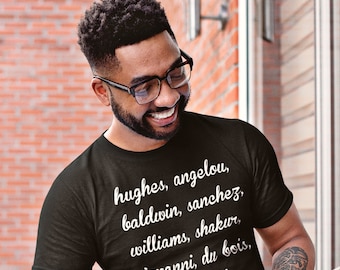 May include: A person wearing a black t-shirt with white text that reads "hughes, angelou, baldwin, sanchez, williams, shakur, giovanni, du bois, def poets". The person is holding a book and smiling.