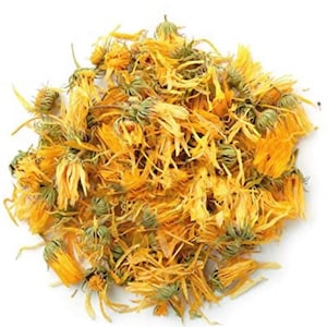 May include: Dried calendula petals, a vibrant yellow-orange color, are scattered on a white background. The petals are loose and appear to be ready for use in crafting or herbal remedies.