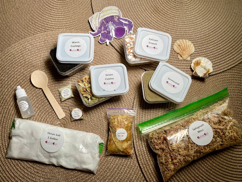 以下が含まれることがあります： ヤドカリの生息地用品のコレクション。ミミズの糞、カルシウムクランチ、グリーサンドの容器が含まれています。海塩、ミズゴケ、落葉、木のスプーンも含まれています。紫色のカニのステッカーも付いています。