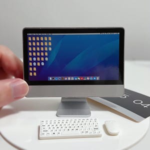 Peut inclure: Un ensemble miniature d'ordinateur de bureau avec un clavier et une souris blancs. L'écran de l'ordinateur affiche un fond bleu avec plusieurs icônes.