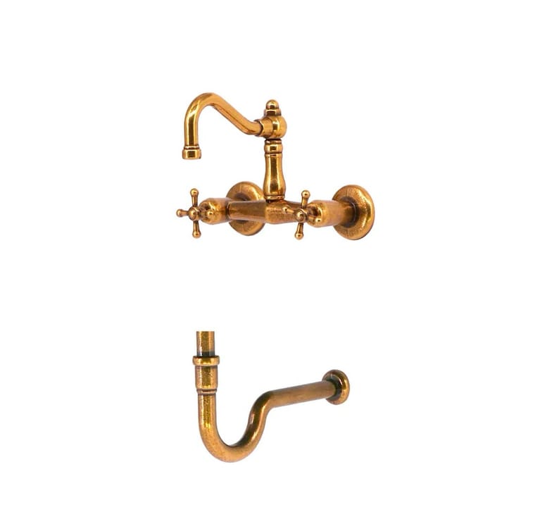 May include: Antique brass kitchen tap set with a curved spout and cross-handle controls. The set includes a wall-mounted tap and a separate curved pipe. The fixtures have a vintage, aged appearance.