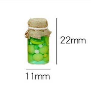 Pu&ograve; includere: Un barattolo di vetro in miniatura con un coperchio di carta marrone e spago, riempito di liquido verde e sfere gialle e bianche. Il barattolo &egrave; largo 11 mm e alto 22 mm.