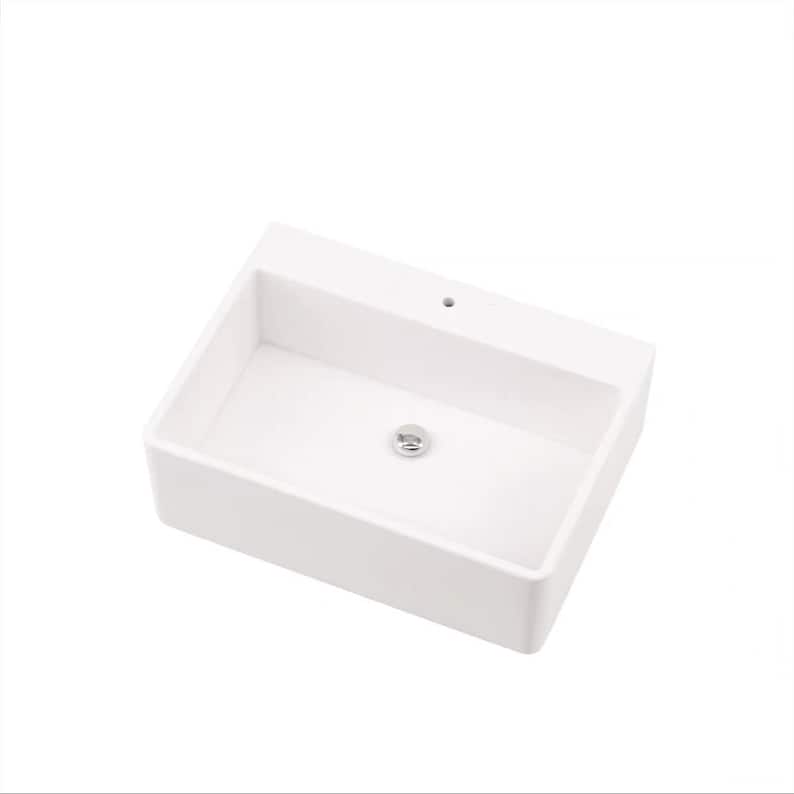 May include: A white ceramic bathroom sink with a single drain hole and a chrome drain stopper.
