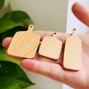May include: Three wooden cutting boards of different sizes, all with a natural wood grain finish. The boards are arranged in a row, with the largest board on the left and the smallest board on the right.