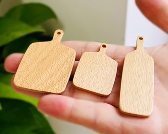 Puede incluir: Tres tablas de cortar de madera de diferentes tamaños, todas con un acabado de grano de madera natural. Las tablas están dispuestas en una fila, con la tabla más grande a la izquierda y la tabla más pequeña a la derecha.