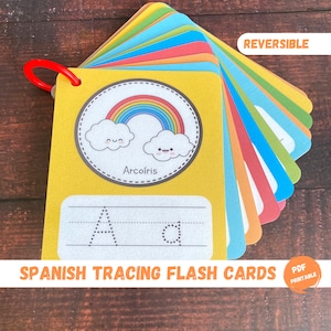 May include: A set of colorful, reversible flash cards for tracing the Spanish alphabet. Each card features a cute illustration and the word for the letter in Spanish. The word "Arcoiris" (rainbow) is visible on one card. The cards are labeled "Spanish Tracing Flash Cards" and "PDF Printable".