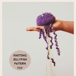 Pode incluir: Padrão de tricô PDF para uma água-viva roxa com tentáculos de fio dourado e branco.