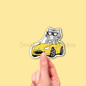 Chat tigré gris conduisant dans un autocollant en vinyle pour voiture Honda S2, accessoire de voiture kawaii, cadeau pour amoureux des chats, voiture s2000, autocollant de course mignon, art de voiture jaune.