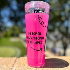 May include: A clear tumbler filled with bright pink liquid. The text "THE POISON" is at the top, with "THE POISON CHOSEN SPECIALLY TO KILL KUZCO" below. Black arrows and swirls decorate the tumbler.