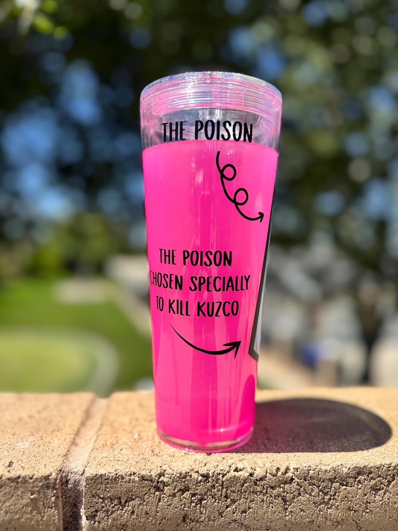 May include: A clear tumbler filled with bright pink liquid. The text "THE POISON" is at the top, with "THE POISON CHOSEN SPECIALLY TO KILL KUZCO" below. Black arrows and swirls decorate the tumbler.