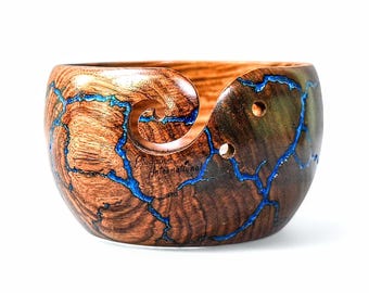 Könnte beinhalten: Holz-Garnschale mit Wirbeldesign und blauen Harzakzenten. Die Schale besteht aus braunem Holz mit natürlicher Maserung. Das blaue Harz füllt die Risse und schafft ein einzigartiges, dekoratives Stück. Der Text "Goddess International" ist sichtbar.