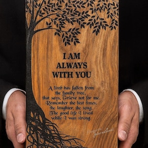 Può includere: Targa in legno con un disegno di albero e le parole "I AM ALWAYS WITH YOU". La targa presenta una silhouette di albero scuro con radici e rami. Il testo sottostante recita: "A limb has fallen from the family tree..."