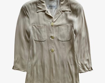 May include: A light beige button-down shirt with two front pockets and three buttons. The shirt has a collar and long sleeves that end at the elbow. The label reads "SPORTMAX".