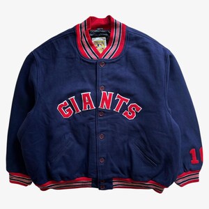May include: A navy blue Giants letterman jacket with red and white striped trim. The word "GIANTS" is embroidered in red across the chest. The number "11" is on the right sleeve. The jacket has a button-up front.