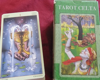 Op de afbeelding: Tarot Celta kaartspeldoos met een groene achtergrond en de tekst "Tarot Celta" in wit. De doos toont een vrouw met een rode sjaal en een gouden ketting die reikt naar een glimmende ster boven een boom.