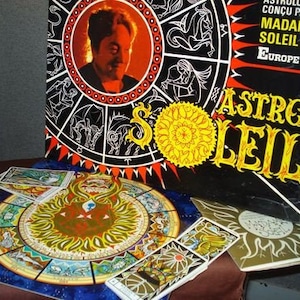 May include: A vintage Astro Soleil board game with a colorful zodiac wheel and playing cards. The game is designed by Madame Soleil and features the text "Astro Soleil" in a bold, stylized font.