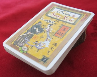 Puede incluir: Una tarjeta amarilla con un borde dorado y una imagen de dos personas con ropa tradicional china. La tarjeta está titulada "L'Oracle San Xin" y el texto "Le soleil" está escrito en francés. La tarjeta está numerada "1".