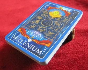 Puede incluir: Una carta de oráculo azul y dorada con el texto "L'Oracle Celeste du Millenium". La carta presenta un diseño circular con símbolos del zodíaco y un sol.
