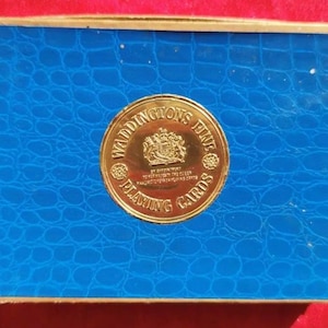 May include: A blue box with a gold border and a gold circular seal that says "Waddingtons Fine Playing Cards".