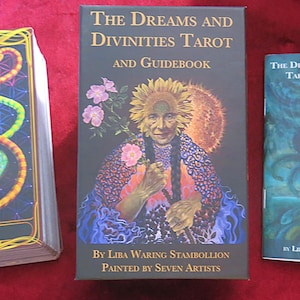 May include: The Dreams and Divinities Tarot deck and guidebook. The deck features a colourful, illustrated card with a figure in a yellow and green costume. The guidebook has a black cover with a woman in a colourful dress and a sunflower crown.