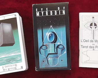 Puede incluir: Un mazo de cartas de tarot y un folleto acompañante se muestran sobre una superficie roja. La caja del mazo es negra con el título "EYE OF MYRDDIN". Un mazo de cartas muestra "L'IMPERATRICE THE EMPRESS". El folleto se titula "L'Oeil de Myrddin ou Tarot des Princes".