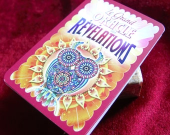 Puede incluir: Una tarjeta roja con una ilustración de un búho colorido y el texto "Le Grand Oracle des Revelations" en francés.