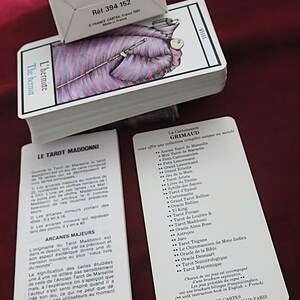 May include: A tarot card deck with a box, branded "GRIMAUD". The cards display an illustration of a robed figure. The box has the text "R&eacute;f. 394 152". Includes instruction booklets. The cards and box are made in France.