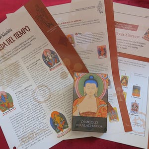 May include: A deck of "Oracolo di Kalachakra" cards with printed materials. The card box shows a portrait of a serene figure. The printed materials include text and illustrations in Spanish.