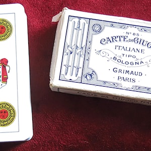 May include: A deck of Italian playing cards with a white and blue box. The cards feature sun and coat of arms designs. The box reads "CARTE DA GIUOCO ITALIANE" and "GRIMAUD - PARIS."