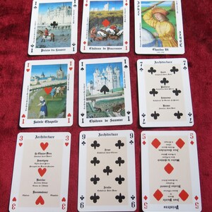 K&ouml;nnte beinhalten: Ein Spielkartenset mit Illustrationen ber&uuml;hmter franz&ouml;sischer Architektur. Die Karten sind von 1 bis 9 nummeriert und beinhalten den Joker. Die Kartenr&uuml;cken zeigen ein sich wiederholendes Muster aus Lilien.