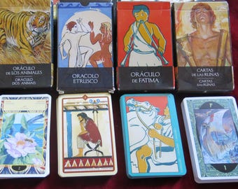 Può includere: Una collezione di otto mazzi di carte da tarocchi, ognuno con un tema diverso. I mazzi includono: Oracolo degli Animali, Oracolo Etrusco, Oracolo di Fatima, Carte delle Rune e Carte delle Rovine. Ogni mazzo ha un design unico e presenta illustrazioni colorate.