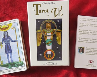 May include: A tarot deck box with the title "Le Tarot de Vie" and the author's name "Christine Roy". The box is white with gold lettering and a colorful image of a winged figure with a halo. The back of the box has text in French about the tarot deck.