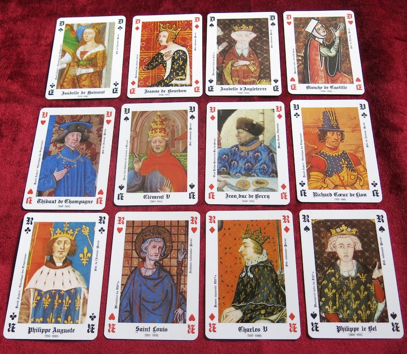 K&ouml;nnte beinhalten: Ein Satz von 12 Spielkarten mit Portr&auml;ts historischer Pers&ouml;nlichkeiten. Jede Karte hat oben links ein schwarzes Pik-Symbol und unten rechts ein rotes Herz-Symbol. Die Karten sind wei&szlig; mit schwarzem Rand und zeigen farbenfrohe Illustrationen historischer Pers&ouml;nlichkeiten.