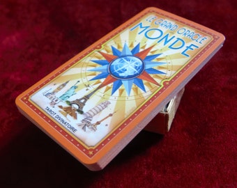 May include: Orange and yellow tarot card with a compass design and the text "Le Grand Oracle Monde Tarot Divinatoire".