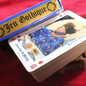 K&ouml;nnte beinhalten: Ein Kartenspiel mit einer blauen Schachtel, auf der "Jeu Gothique" steht. Die oberste Karte des Spiels zeigt ein Gem&auml;lde eines Mannes in einem blauen und goldenen Gewand, der auf einem Bett liegt. Die Karte tr&auml;gt die Aufschrift "Jean duc de Berry" unten.
