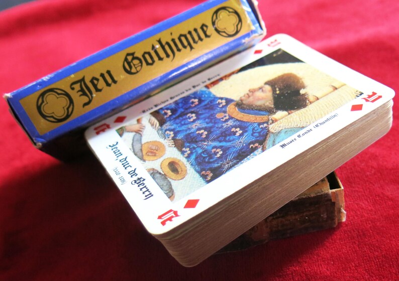 K&ouml;nnte beinhalten: Ein Kartenspiel mit einer blauen Schachtel, auf der "Jeu Gothique" steht. Die oberste Karte des Spiels zeigt ein Gem&auml;lde eines Mannes in einem blauen und goldenen Gewand, der auf einem Bett liegt. Die Karte tr&auml;gt die Aufschrift "Jean duc de Berry" unten.