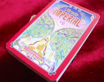May include: A red and white card with the text "L'Oracle Imperial" in a gold and blue font. The card features a colorful illustration of a Buddha sitting on a throne with a peacock and other figures.