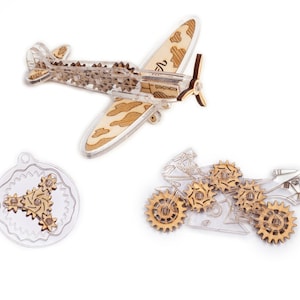 May include: Three wooden models of vehicles with intricate gear mechanisms. A plane with camouflage pattern, a motorcycle, and a circular model with three gears.