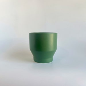 May include: A dark green ceramic planter with a slightly flared rim and a rounded base.