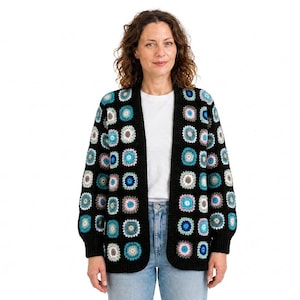 Könnte beinhalten: Eine langärmelige, offene Strickjacke mit schwarzer Basis und einem wiederkehrenden Muster aus mehrfarbigen Häkel-Granny-Squares in Blau-, Weiß- und Grautönen. Das Kleidungsstück hat einen einfarbigen schwarzen Rippstricksaum an der Vorderseite.