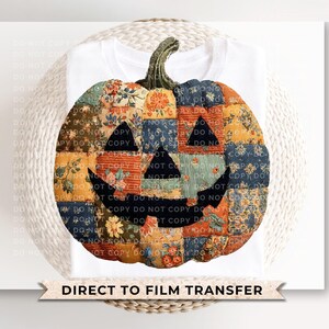 May include: A white t-shirt featuring a patchwork pumpkin design. The pumpkin is made of various fabric patterns in orange, blue, and floral prints, with a carved face. The text "DIRECT TO FILM TRANSFER" is at the bottom.