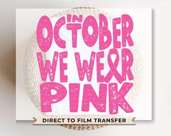 May include: Pink and white graphic design with the text "In October We Wear Pink" and "Direct to Film Transfer".