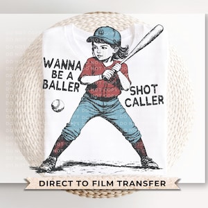 May include: A white t-shirt with a red, white, and blue baseball player illustration. The text "Wanna be a baller Shot caller" is printed on the shirt.