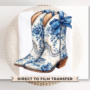 May include: A pair of white cowboy boots with a blue floral pattern and a blue bow. The boots are on a white background with the text "DIRECT TO FILM TRANSFER" at the bottom.