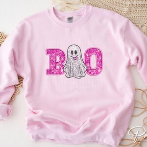 May include: Pink sweatshirt with a sparkly pink ghost and the word "BOO" in sparkly pink letters.